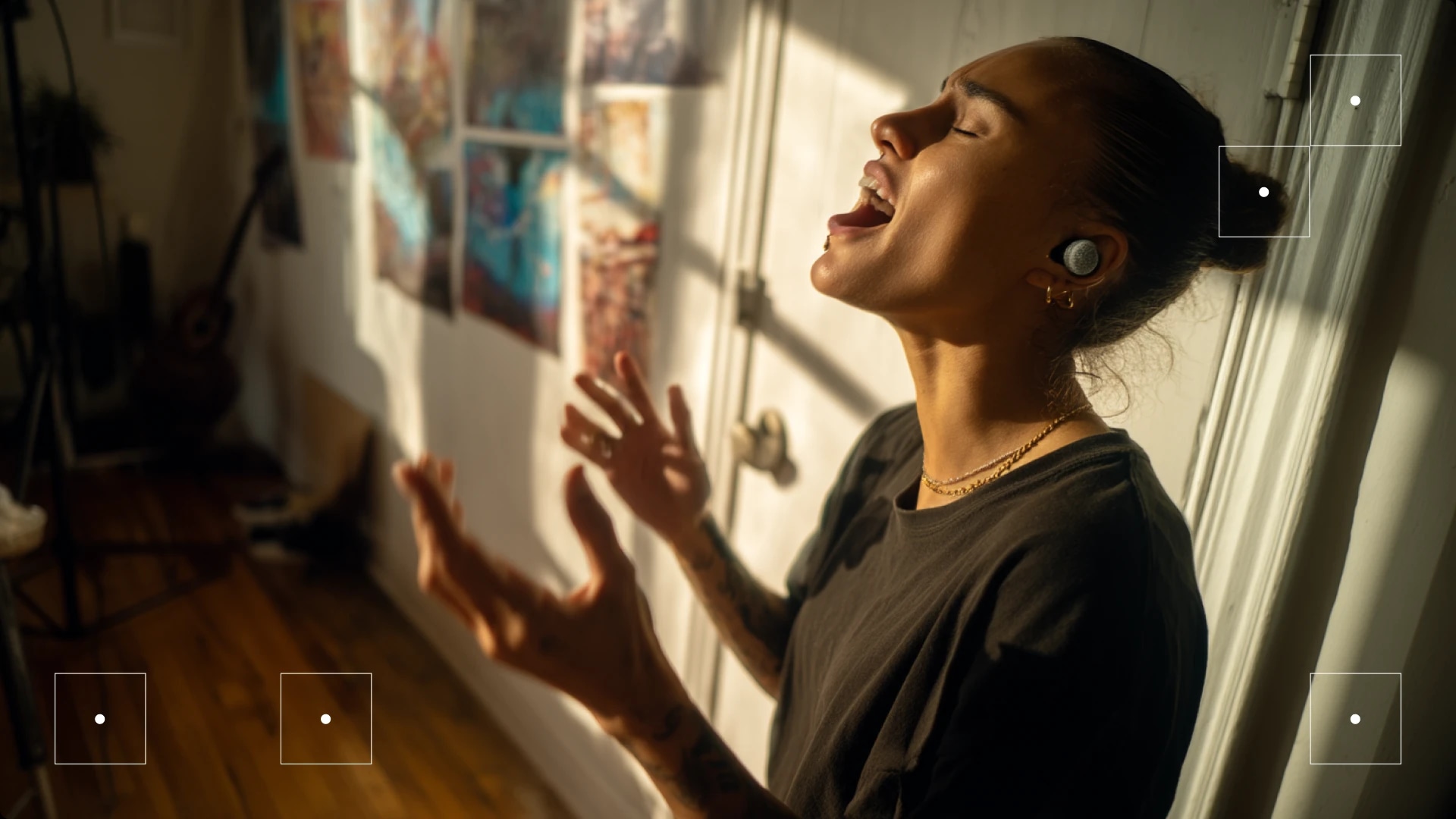A woman singing passionately with her eyes closed, standing near a window with sunlight streaming in.